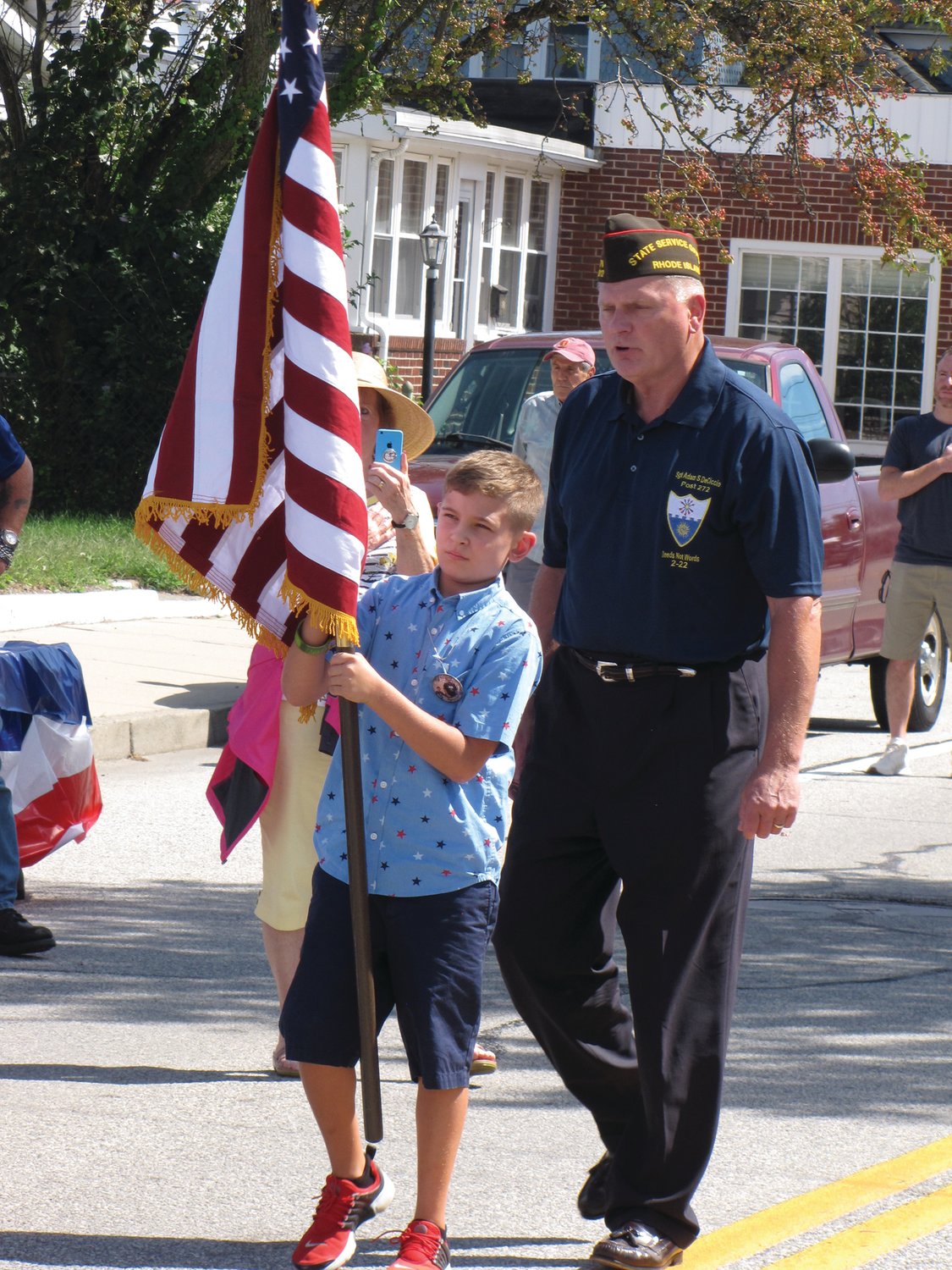 PRESENTING THE COLORS: Gunner DeCiccio, accompanied by Raymond Denisewich of the VFW, carries the American flag at the outset of Saturday’s ceremony.